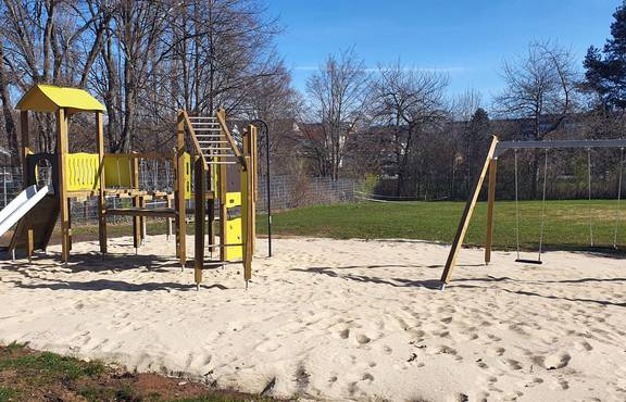Spielplatz mit Rutsche, Kletterstrecke, Schaukel und einem großen Sandkasten.
